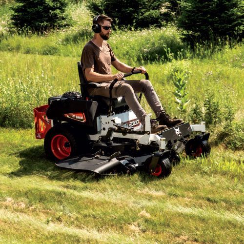 Man on A White Zero-Turn Mower Cutting Tall Grass in A Field, Wearing Headphones — Tracserv in Dubbo, NSW