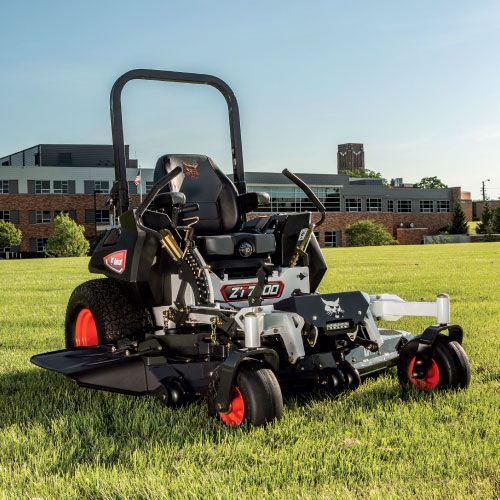 Zero-Turn Lawn Mower on A Grassy Field with A Building in The Background. Features Orange Wheels and A Black Seat — Tracserv in Dubbo, NSW
