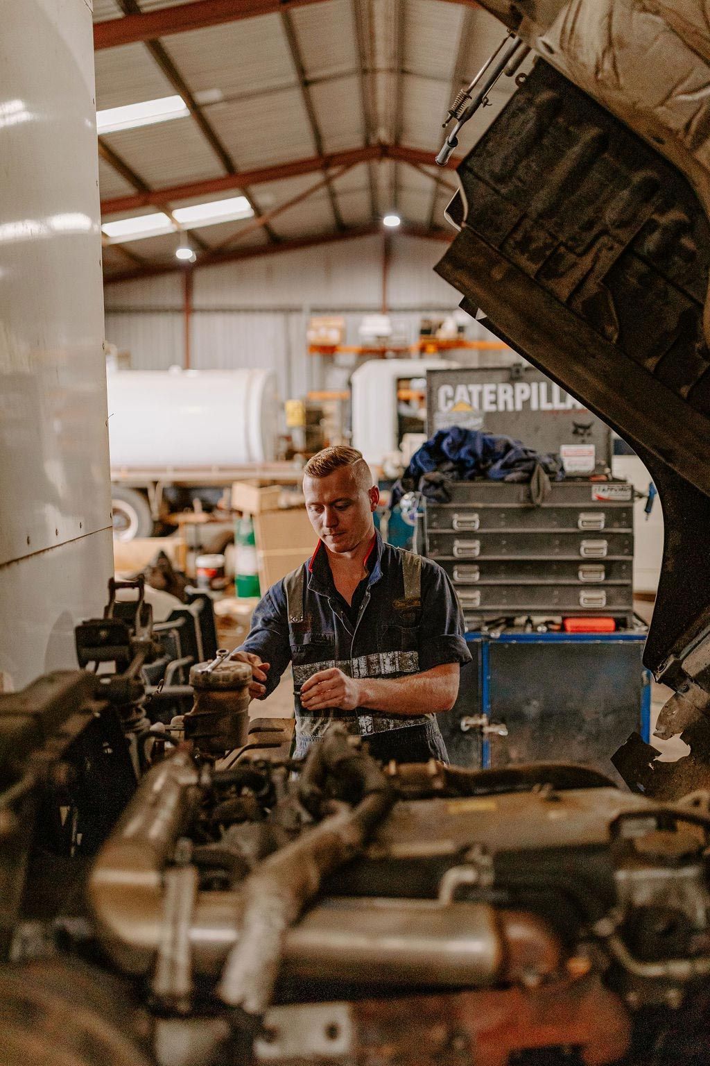 A Man Is Working On A Truck Engine In A Garage — Tracserv in Bourke, NSW