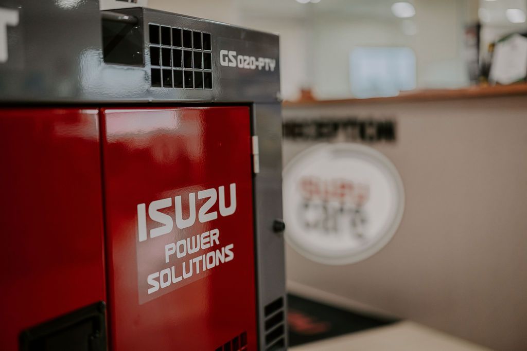 A Red Isuzu Power Solutions Generator Is Sitting On A Table In A Room — Tracserv in Mudgee, NSW