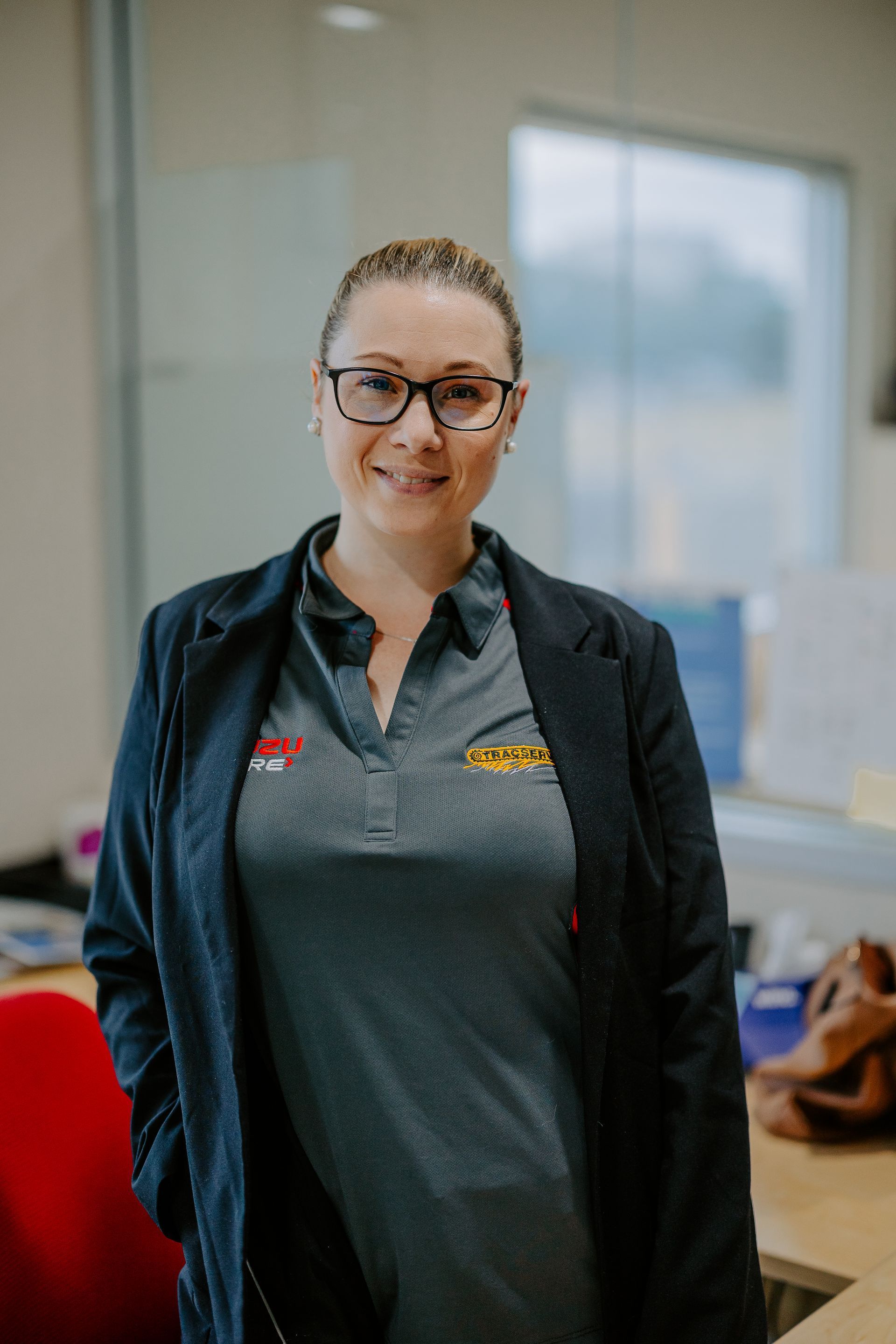 A Woman Wearing Glasses And A Jacket Is Standing In An Office — Tracserv in Orange, NSW