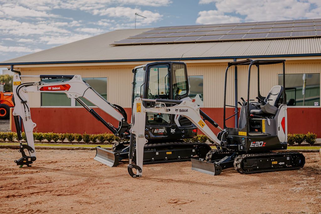 Two Excavators Are Parked In Front Of A Building — Tracserv in Bathurst, NSW