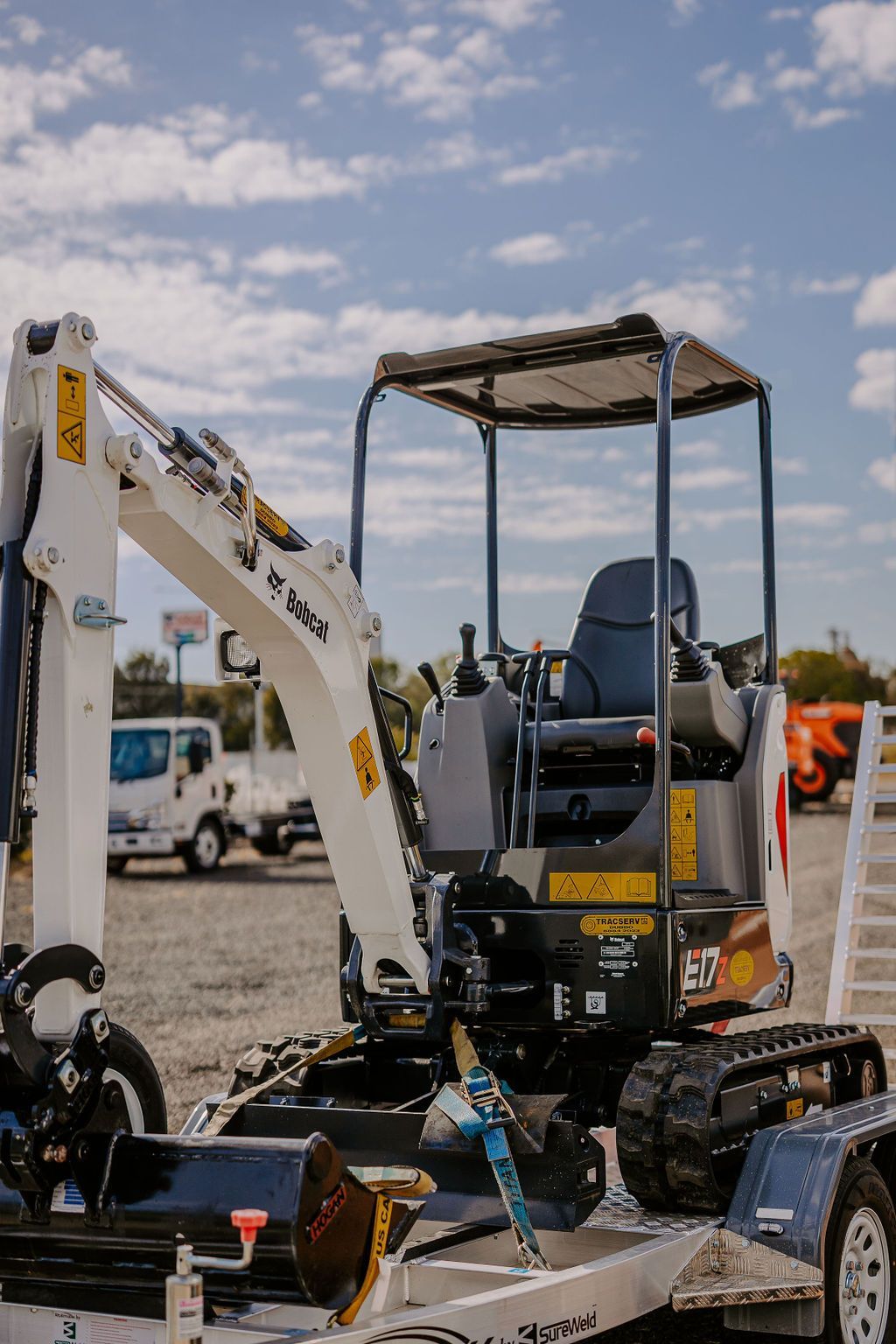 A Small Excavator Is Parked On A Trailer In A Parking Lot — Tracserv in Orange, NSW