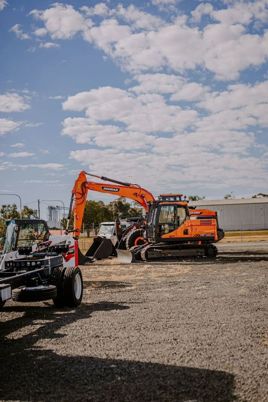 A Large Orange Excavator Is Parked In A Gravel Lot — Tracserv in Bourke, NSW