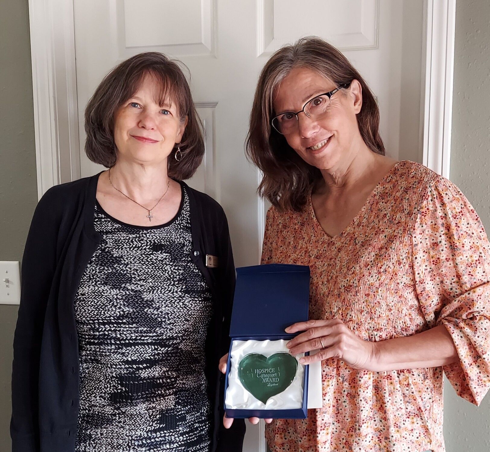Three women are standing next to each other holding a heart shaped box.
