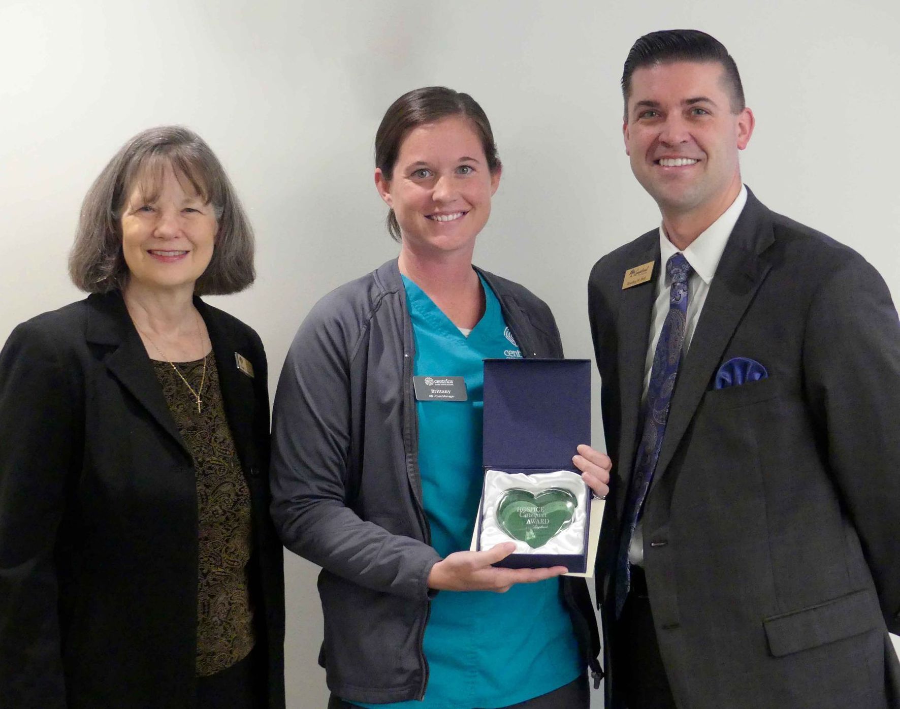 Three women are standing next to each other holding a heart shaped box.