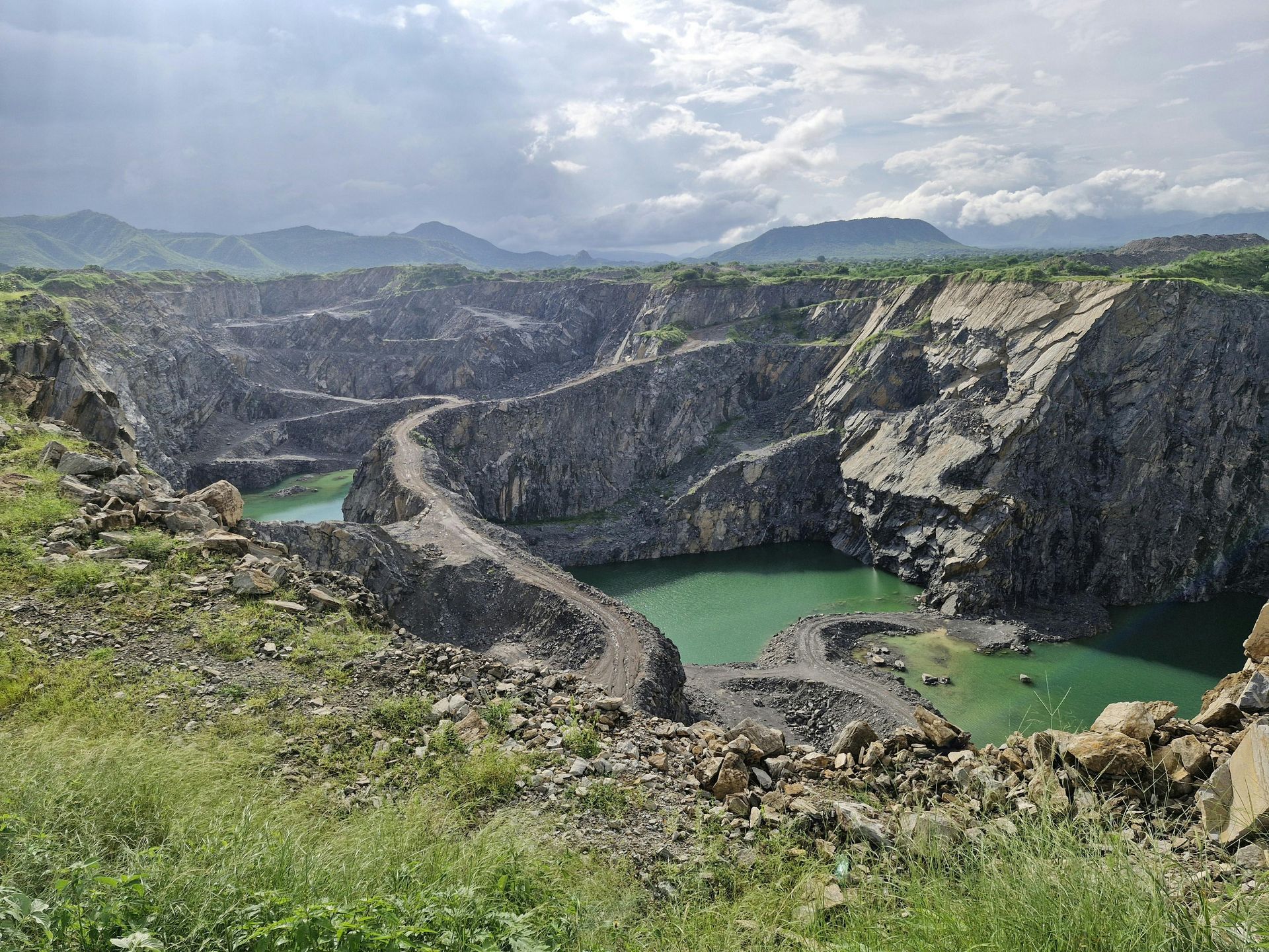 A deep, water-filled quarry with rocky walls under a cloudy sky.