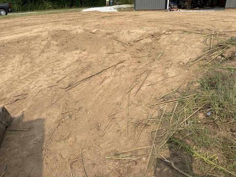 A gray metal building with an open door and gravel driveway next to grassy field.