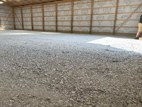Gravel-covered floor inside a wooden framed building with a partially visible person standing.