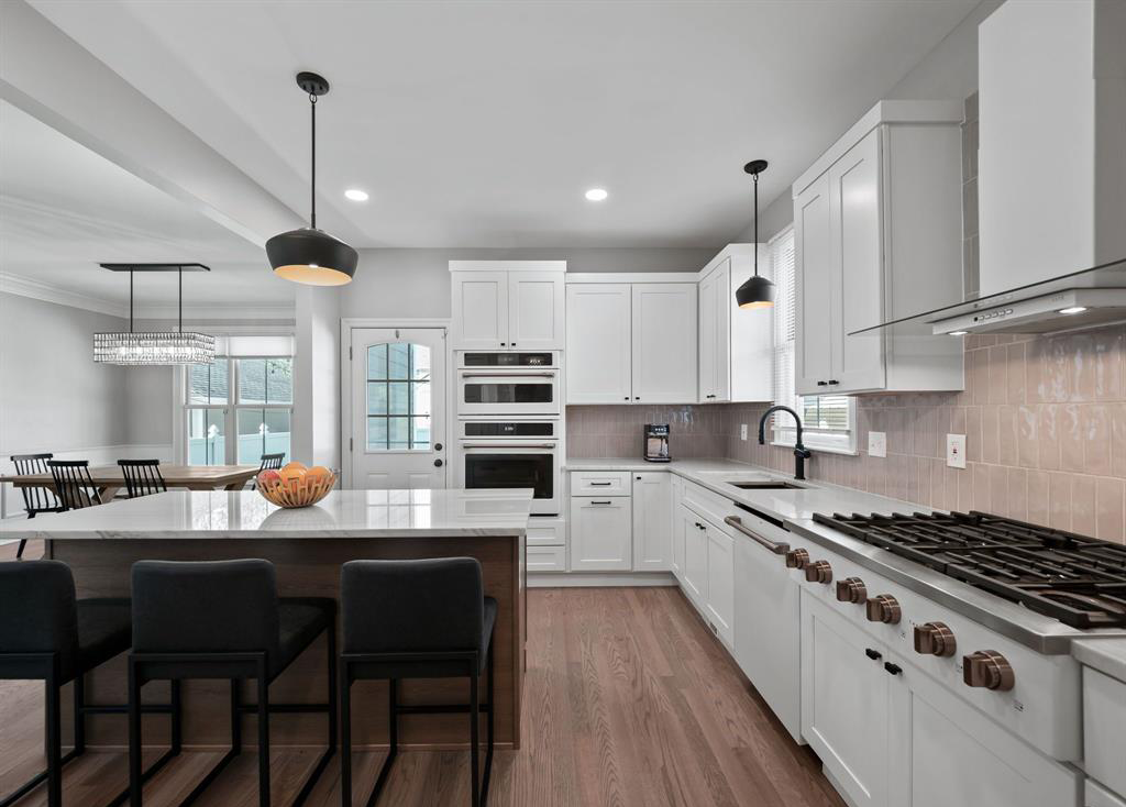 a kitchen with white cabinets , a refrigerator , a sink , and a table .