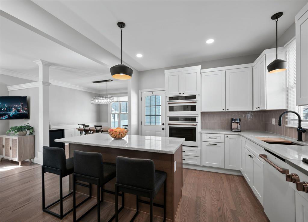 A kitchen with white cabinets and stainless steel appliances and a large island.