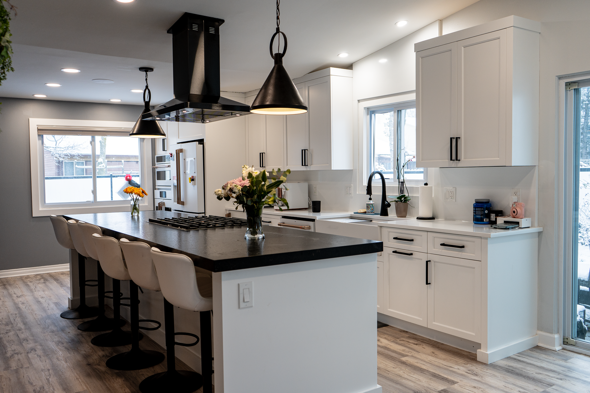 a kitchen with white cabinets , black counter tops , and a large island .