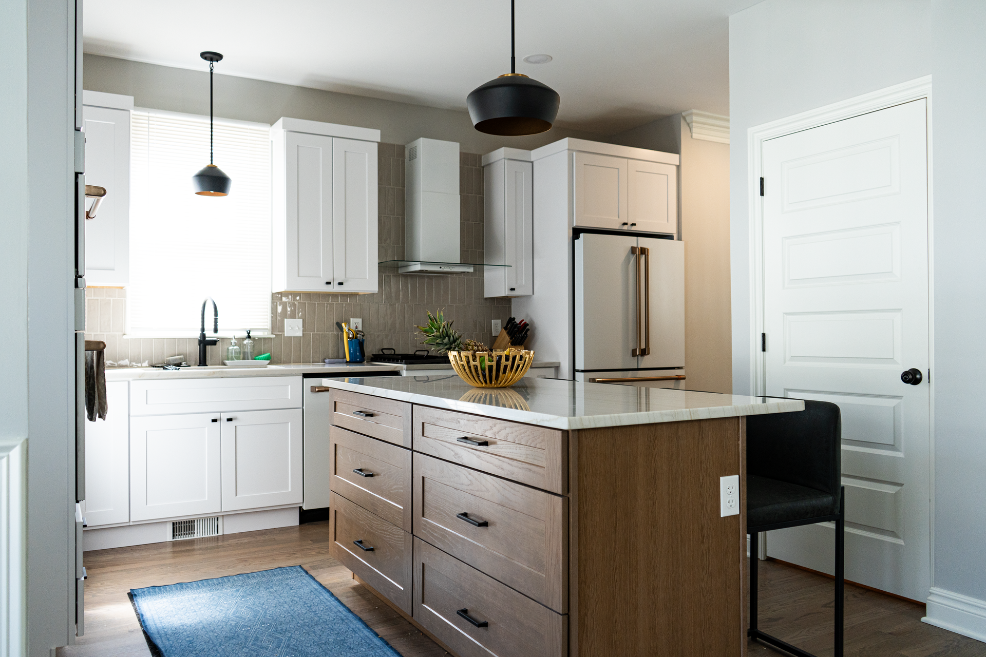 a kitchen with white cabinets , a refrigerator , a sink , and a table .