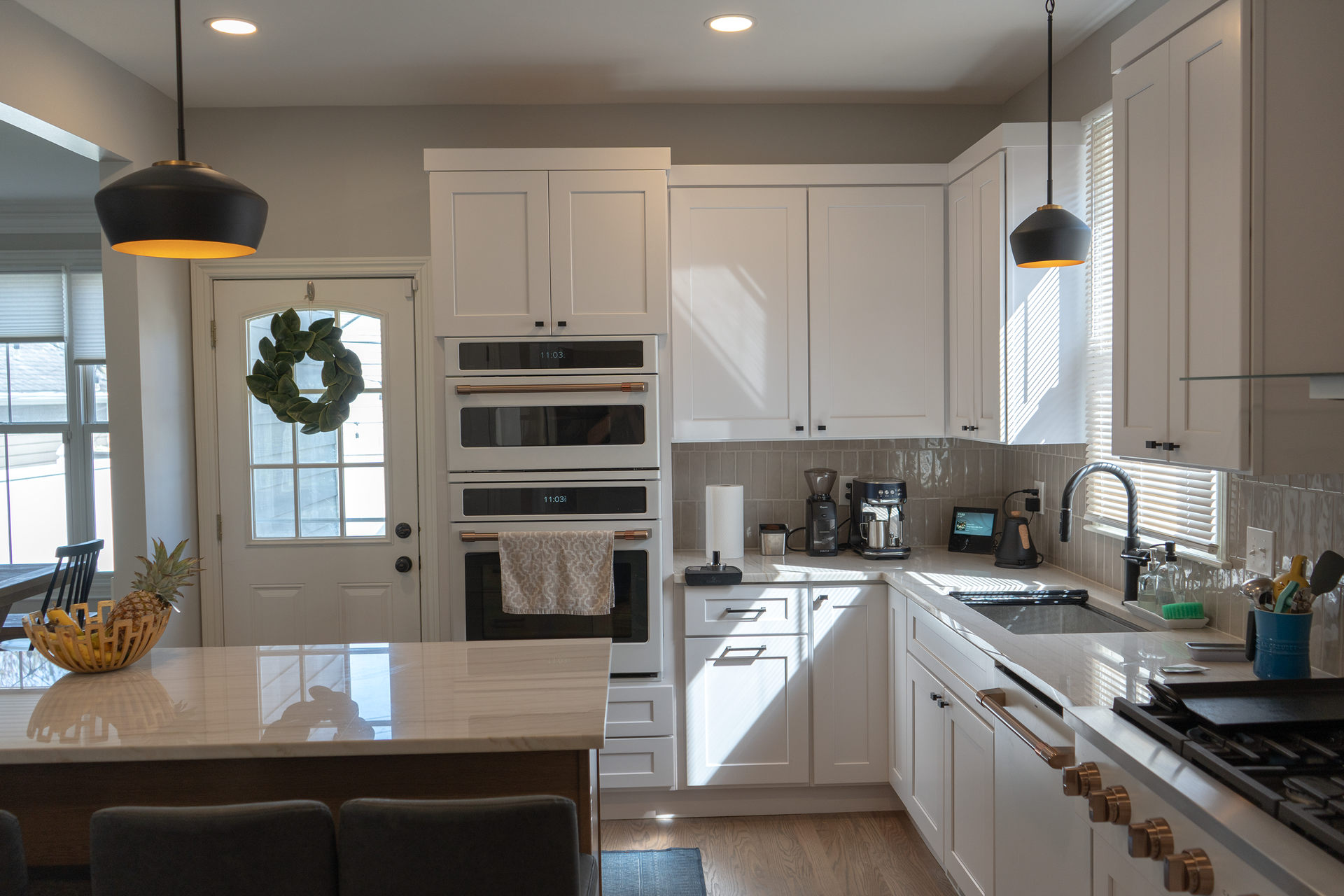 A kitchen with white cabinets, stainless steel appliances, and a wreath on the door.