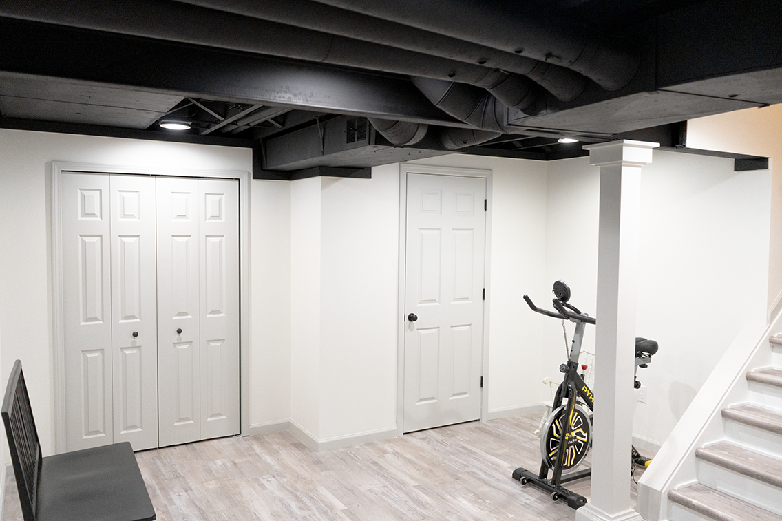 A basement with a bicycle and stairs in it.