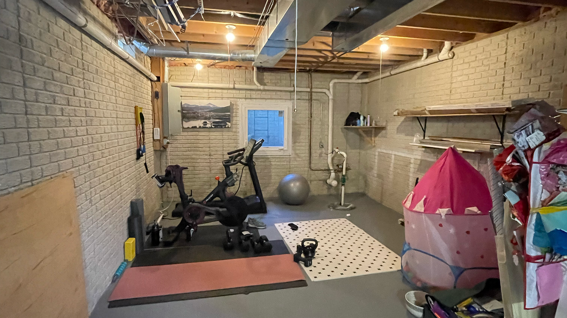 a basement gym with a treadmill , exercise ball , and balloons nvrrete