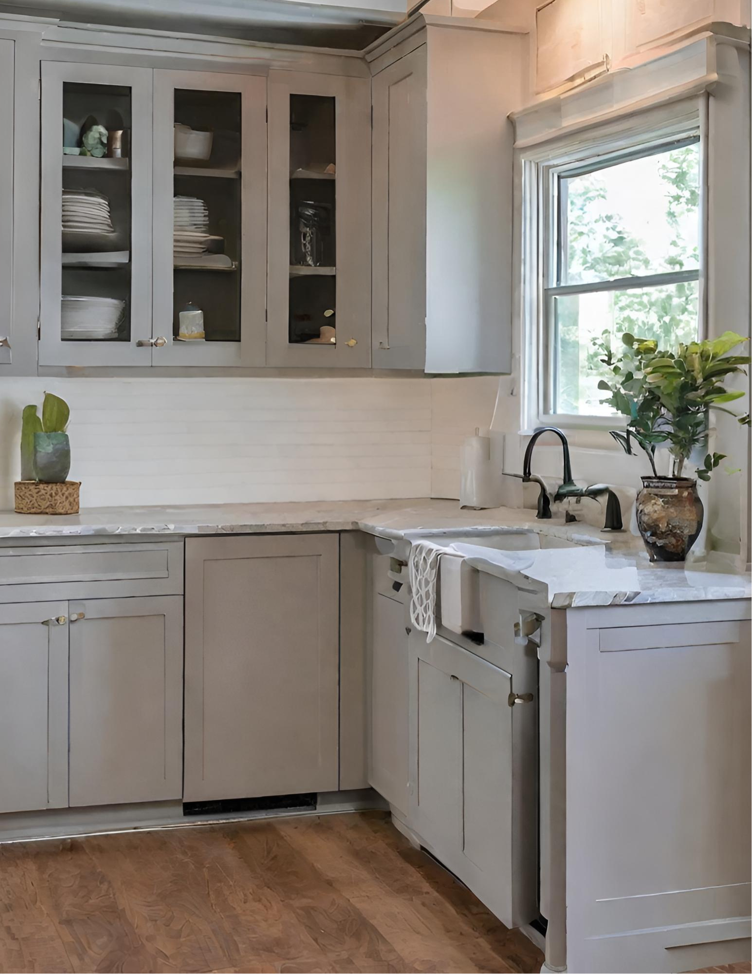 a kitchen with gray cabinets , a sink , and a window .