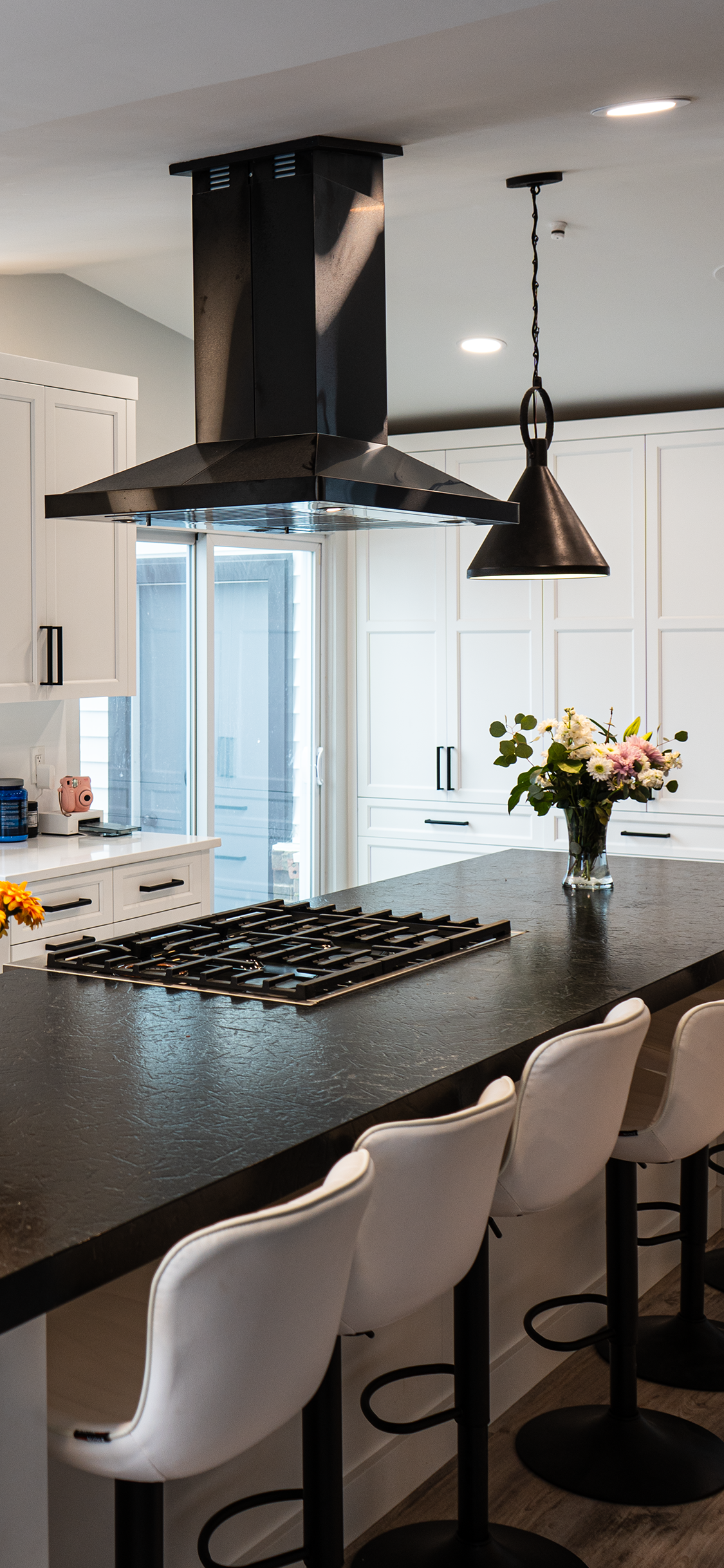 a kitchen with a stove top oven , stools , and a black counter top .