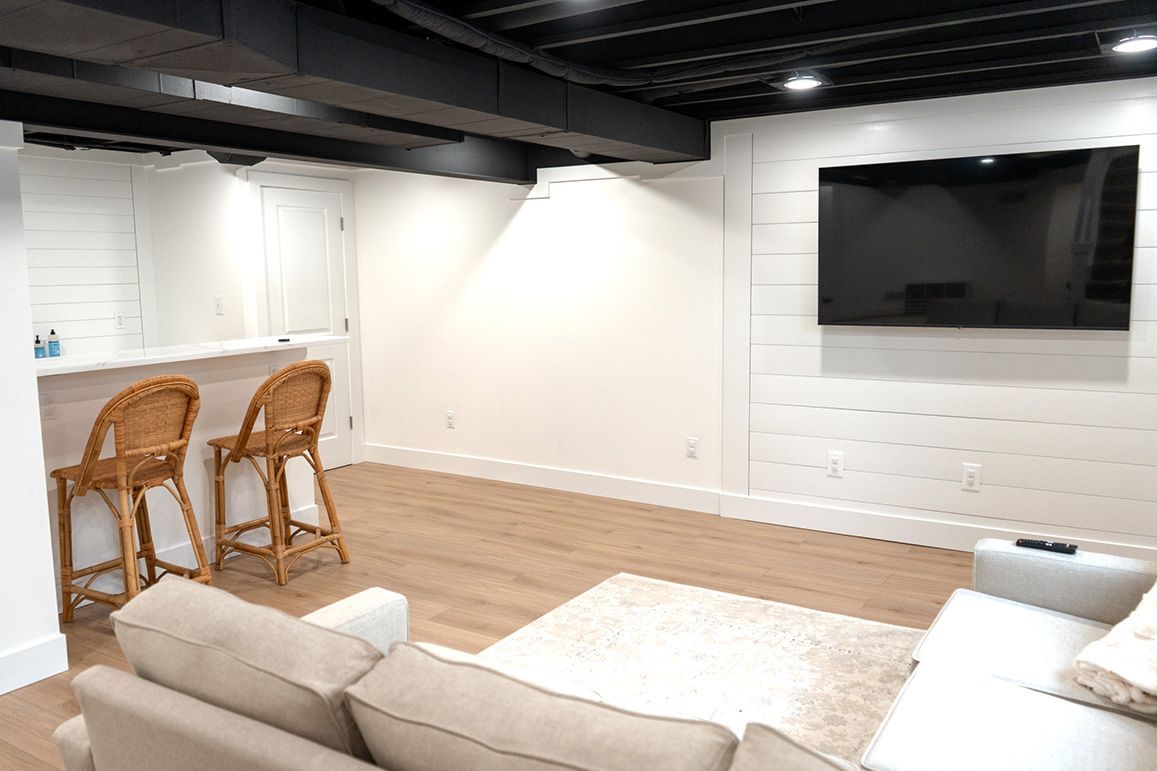 A living room with a couch , bar stools and a flat screen tv.