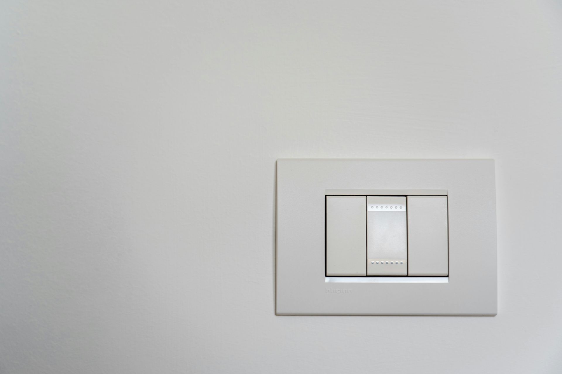 A white light switch on a white wall.