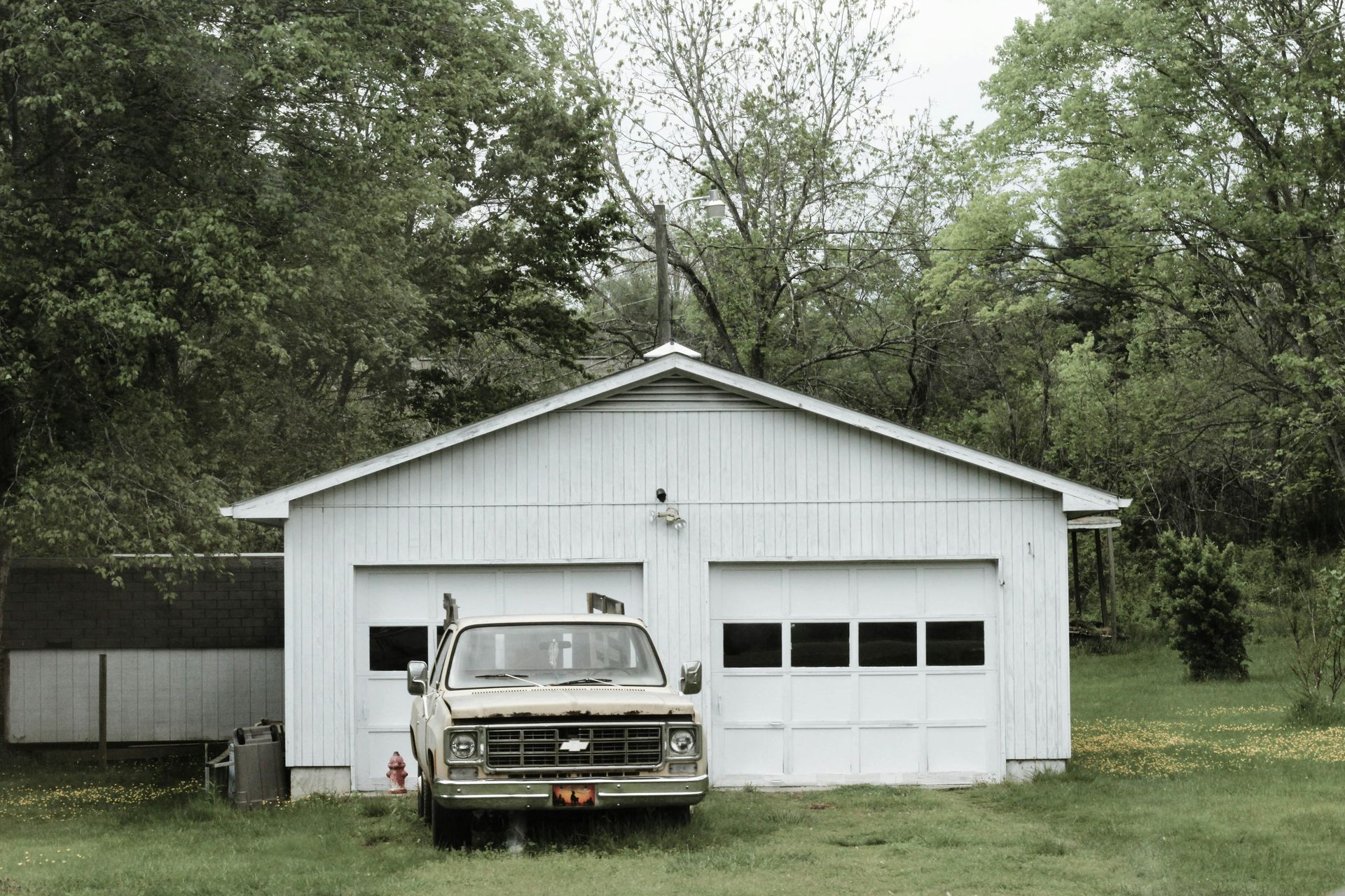 A white truck is parked in front of a white garage