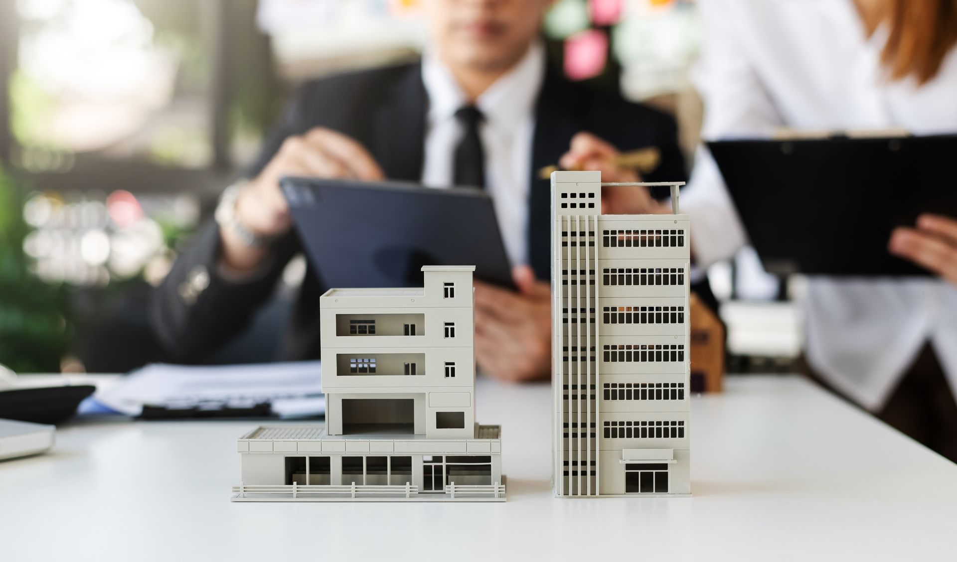 a man is sitting at a table with a tablet and a model of a building nvrrete real estate 