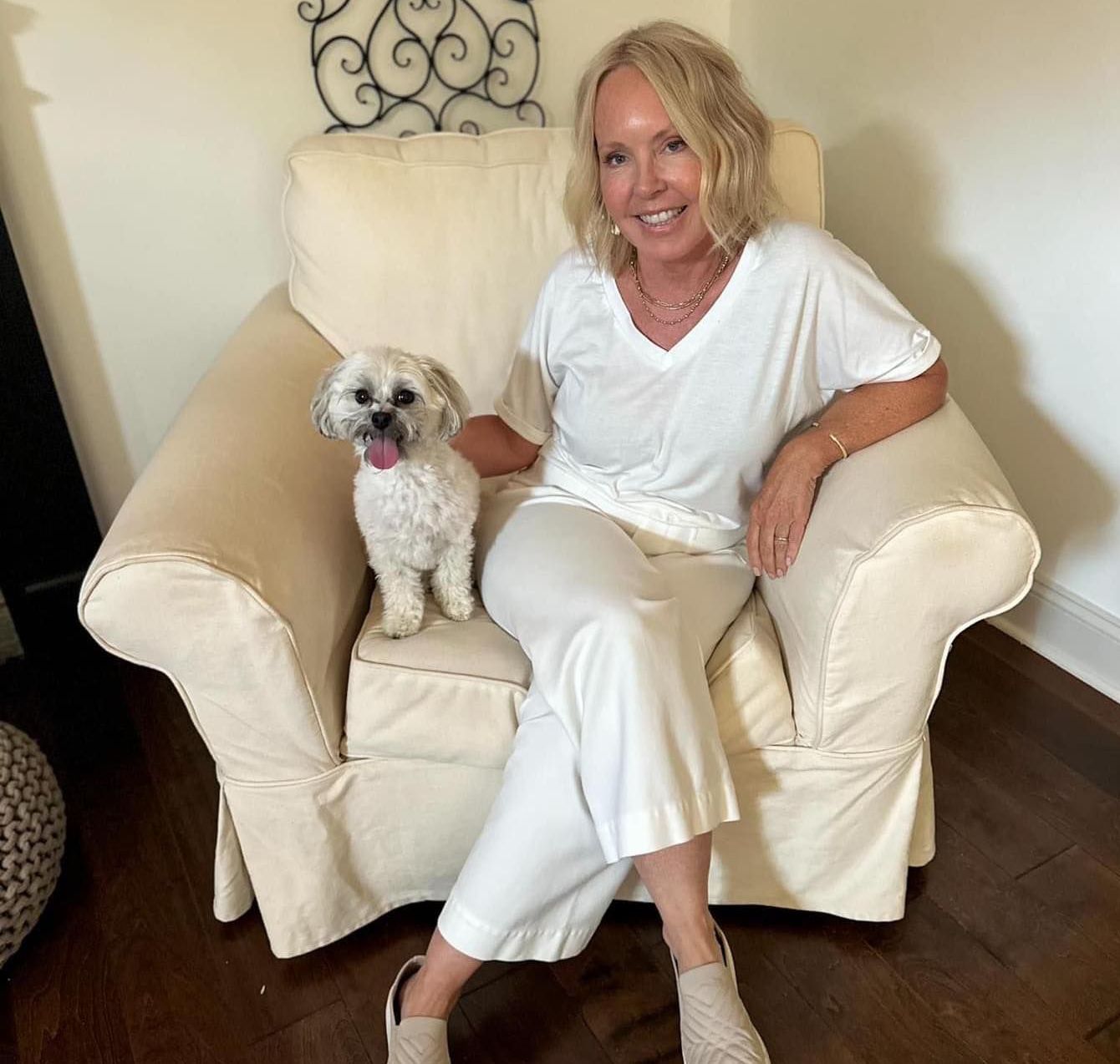 A woman is sitting in a chair with her dog