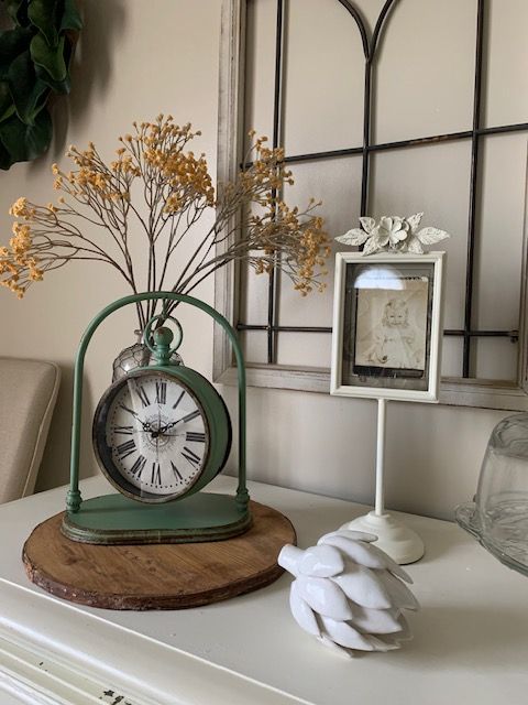A clock is sitting on a table next to a vase of flowers.