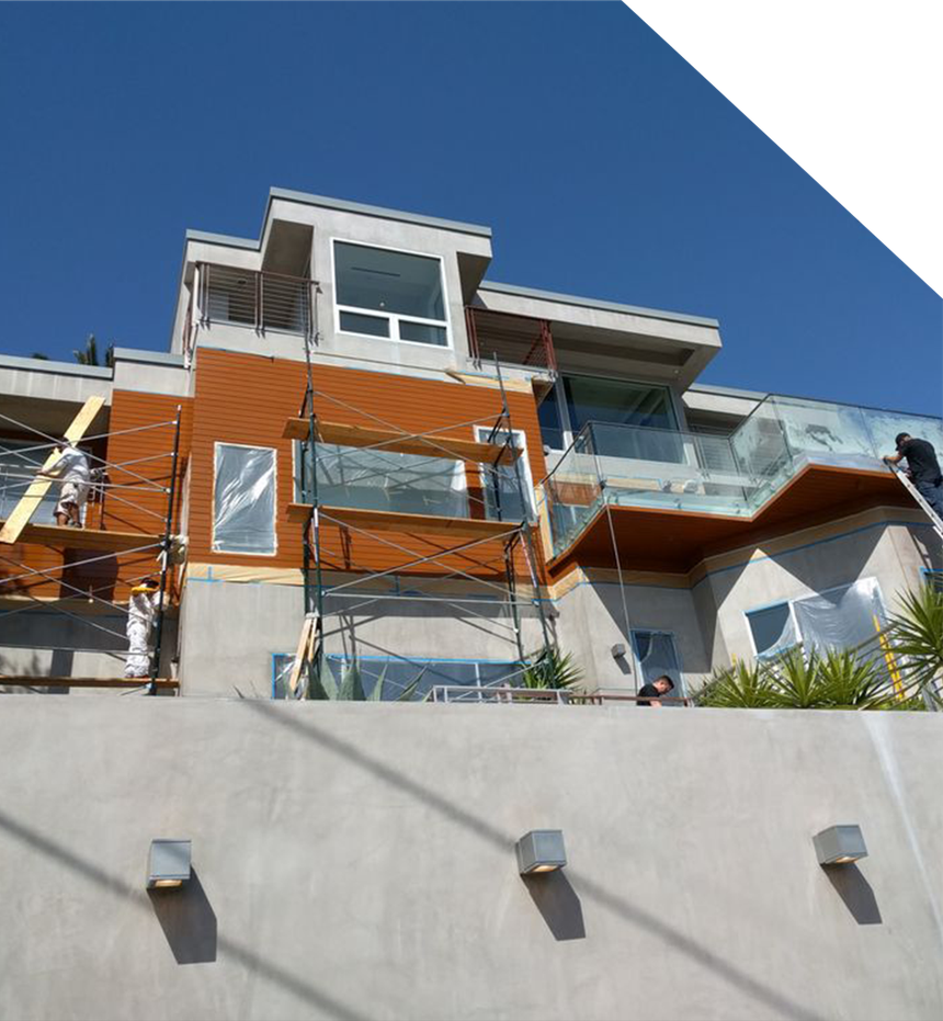 Modern multi-story building under construction; scaffolding; orange siding; blue sky.