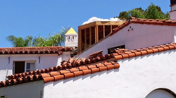 White stucco buildings with red-tiled roofs, a yellow tower, and blue sky.