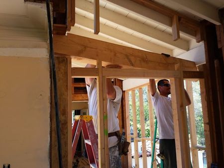 Two people building a wooden frame. White shirts. Construction setting.