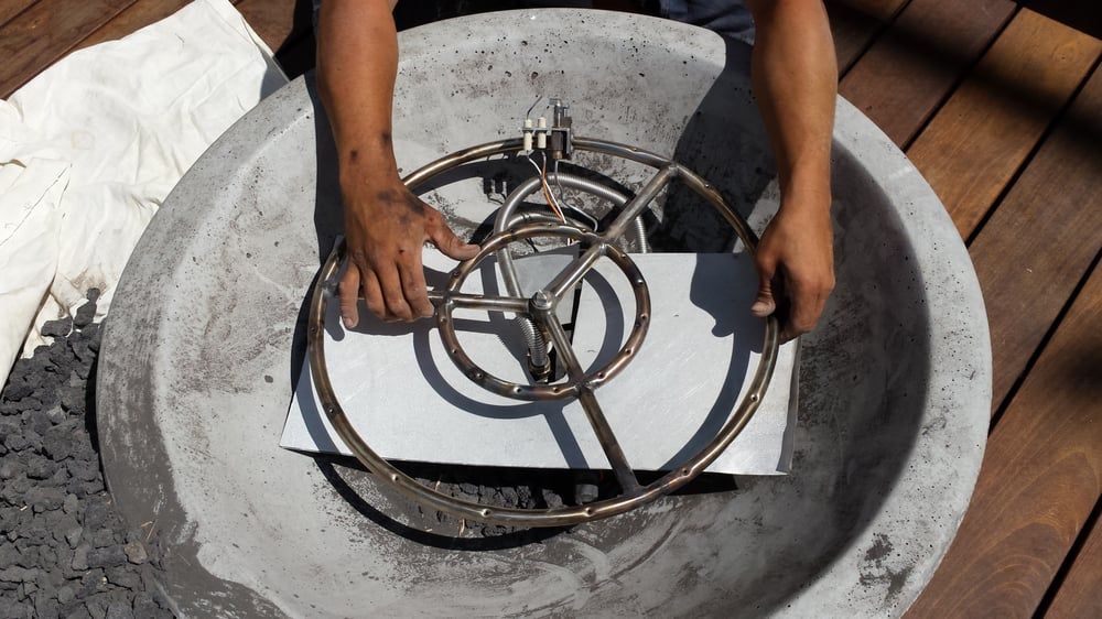Person installs fire ring in a concrete fire pit on a wooden deck.