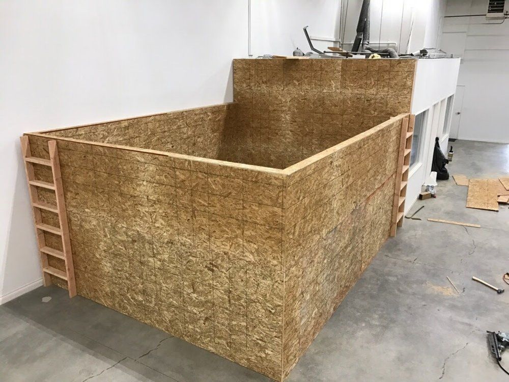 A large wood-paneled structure under construction, with a ladder on the side.