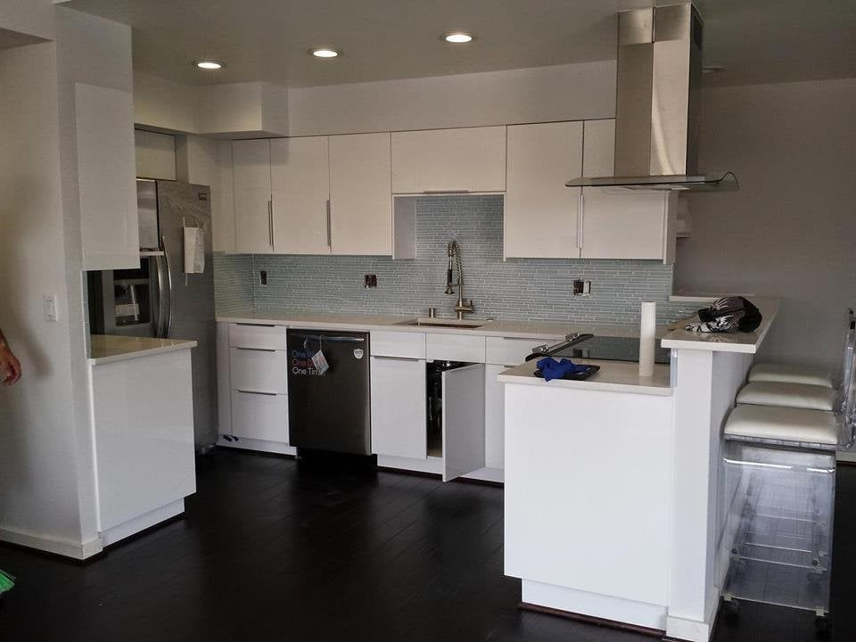 White kitchen with stainless steel appliances, blue backsplash, and a breakfast bar.
