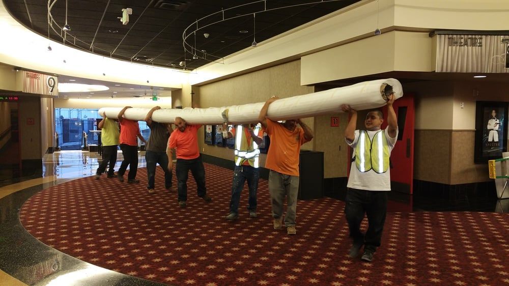 People carrying a long, white cylindrical object through a movie theater hallway.