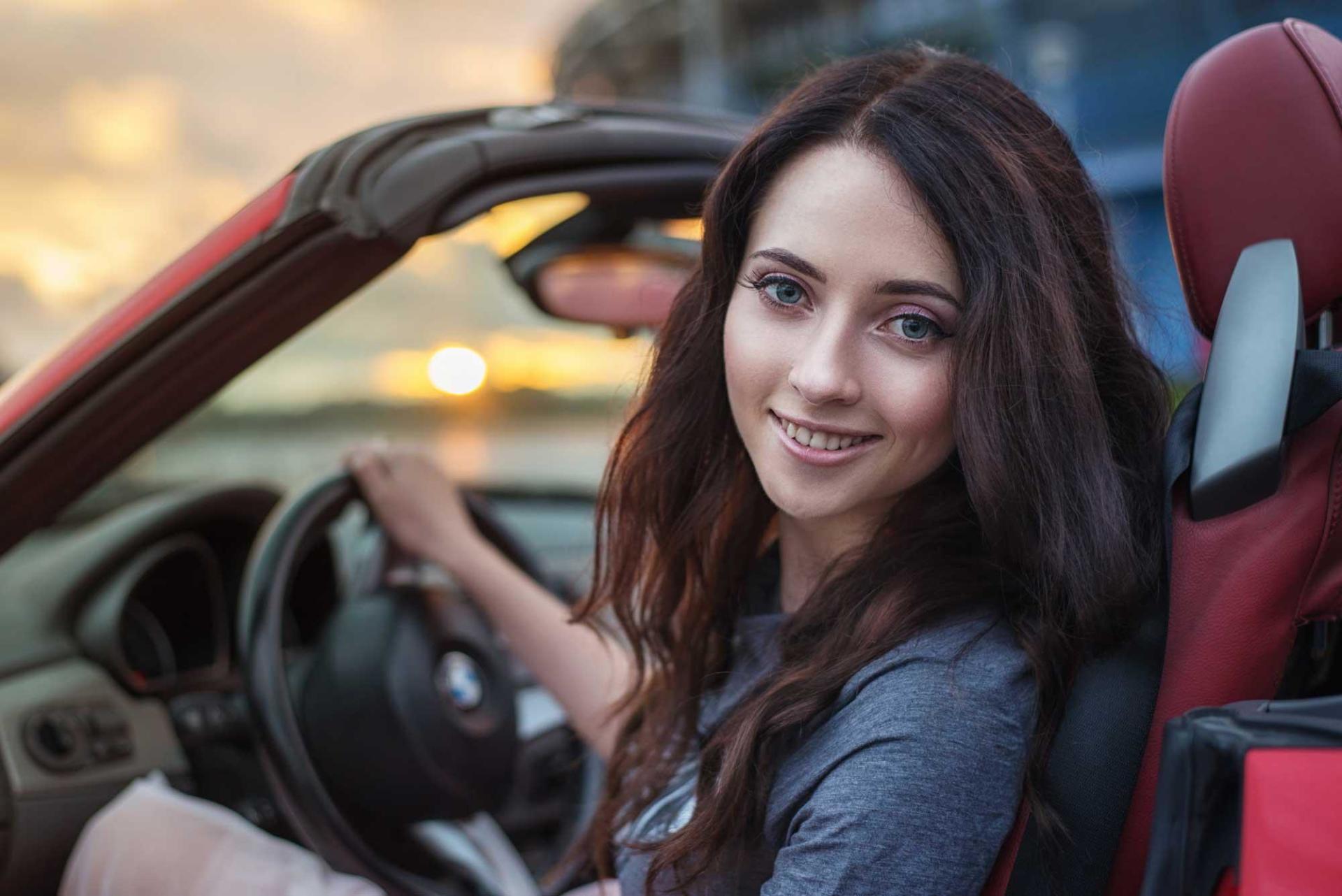 A woman is sitting in a red convertible car.