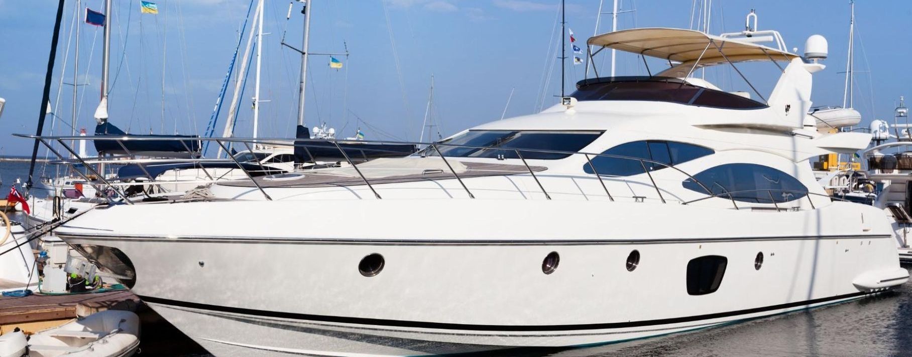 A large white yacht is docked in a marina.