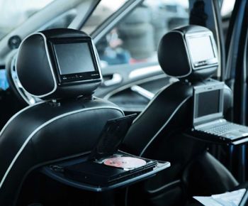 The back seat of a car has a dvd player and a laptop