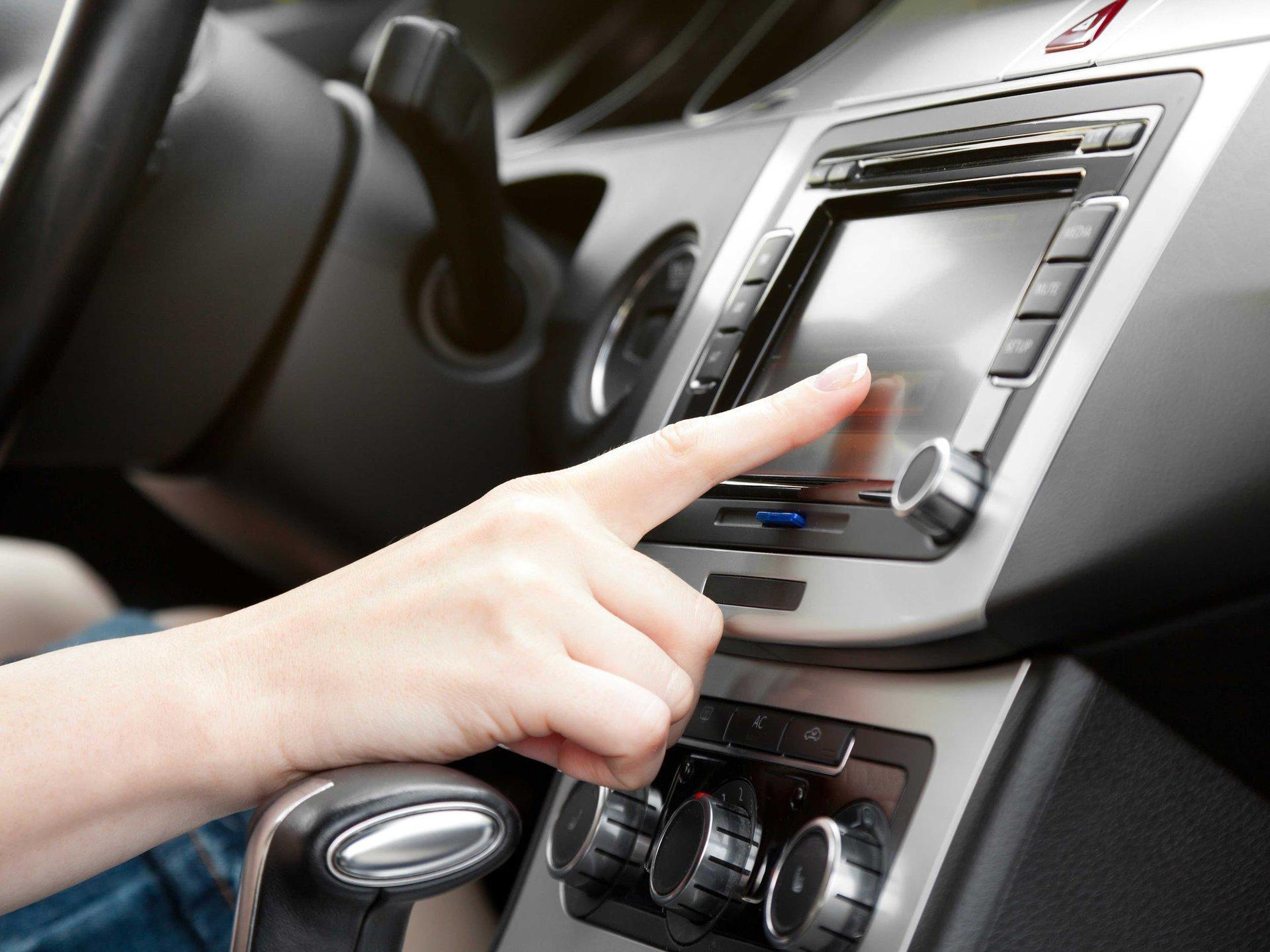 A person is pressing a button on a car radio