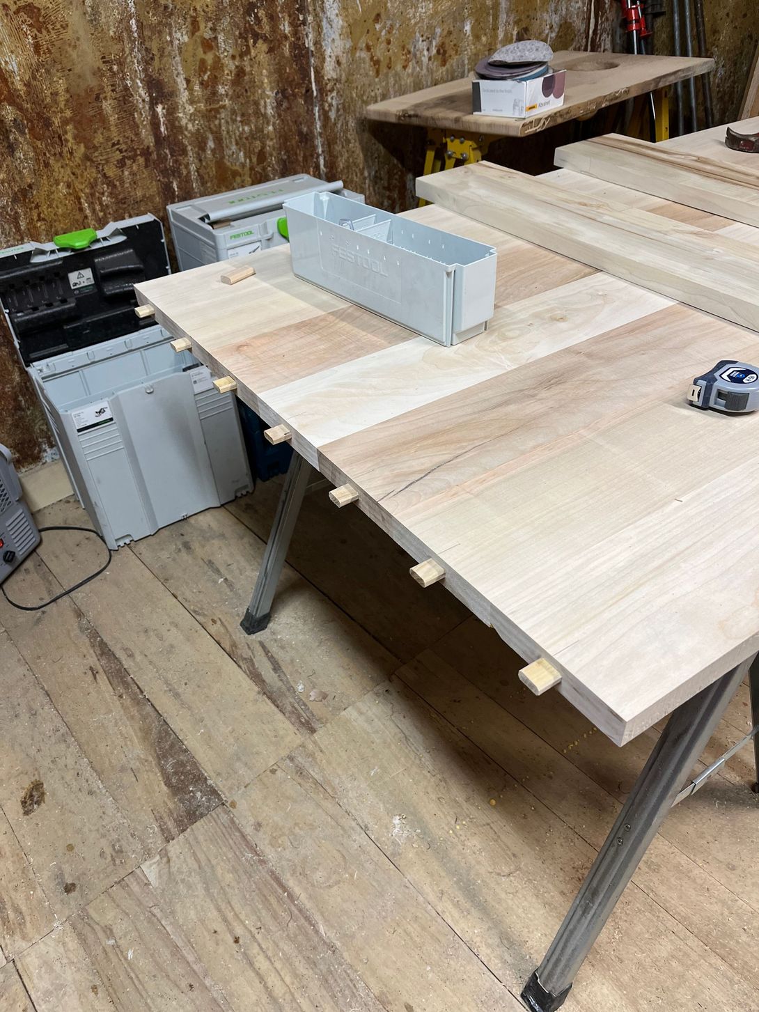 Wooden tabletop in a workshop, assembled with wooden dowels, various tools.