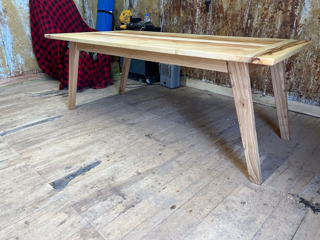 Wooden table with angled legs on a wooden floor.