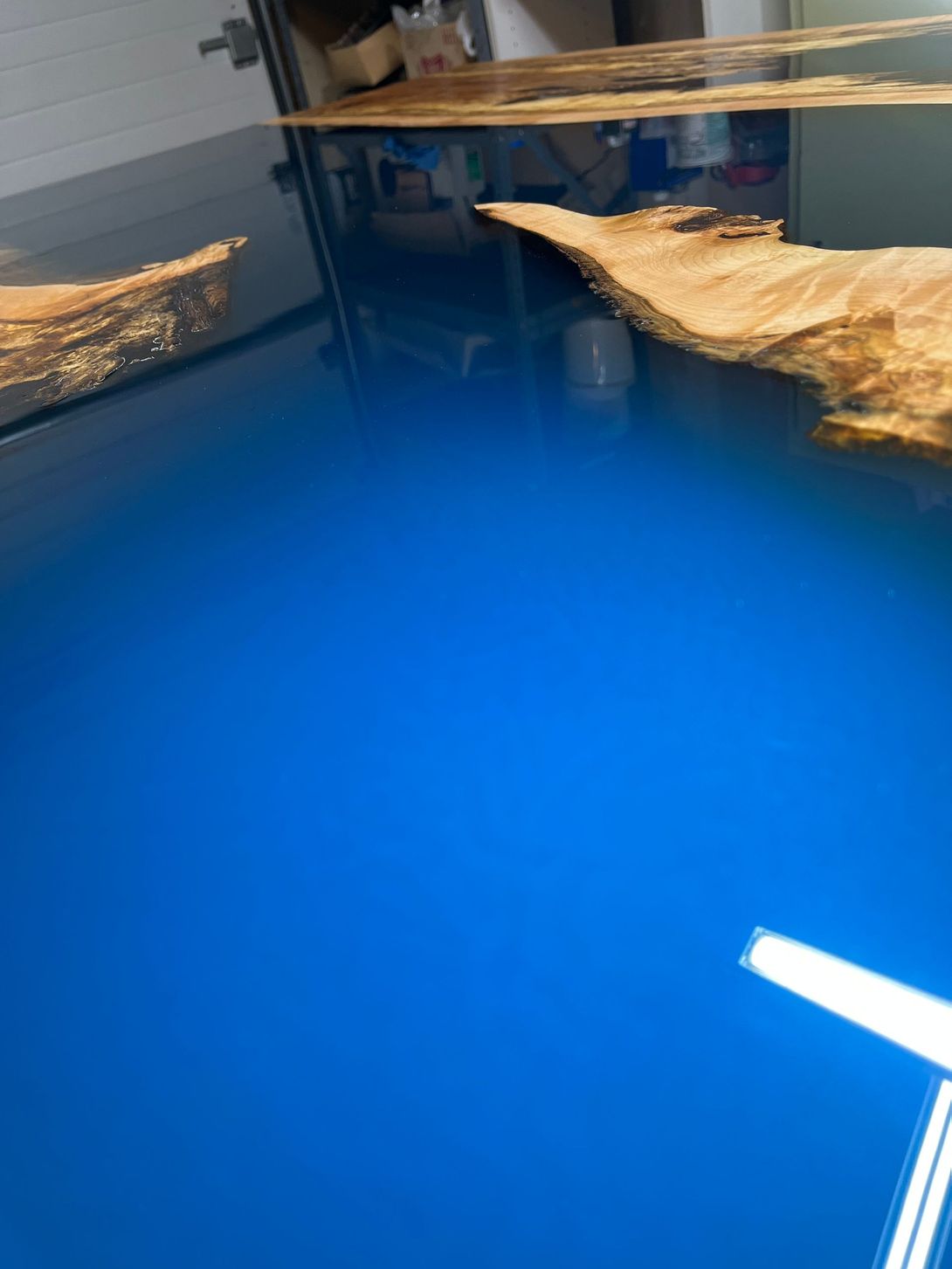 Blue epoxy resin river table with wood grain.