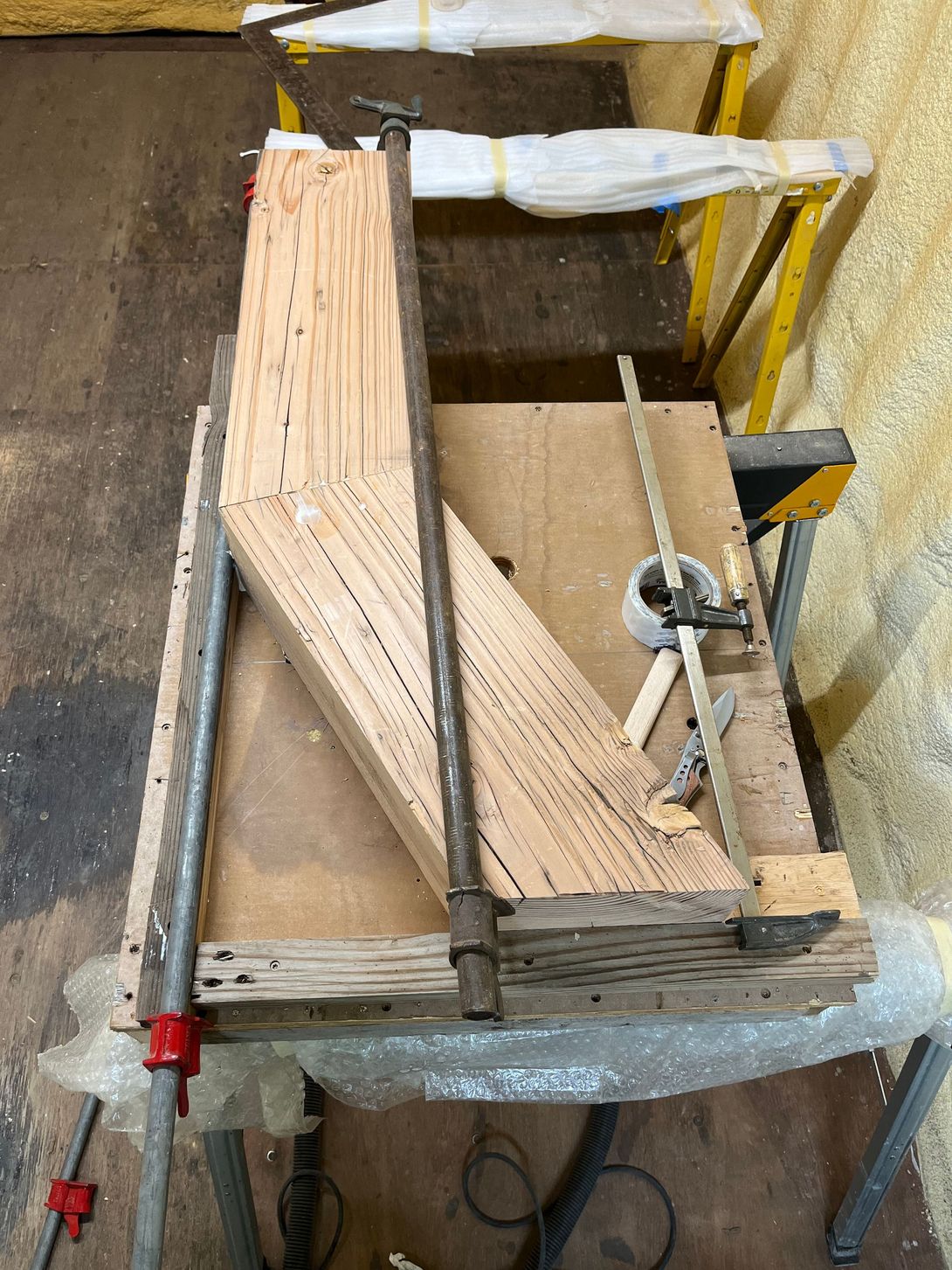 Wooden woodworking project clamped on a workbench with tools.
