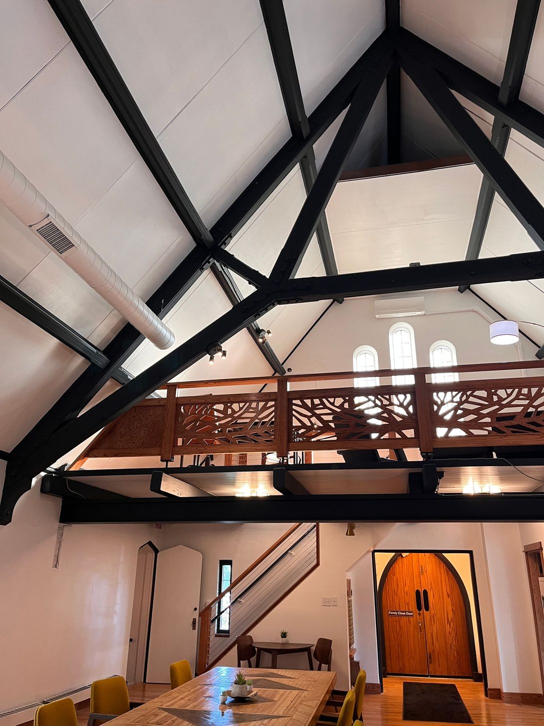 Interior view of a room with a high, black-beamed ceiling and a second-story balcony.