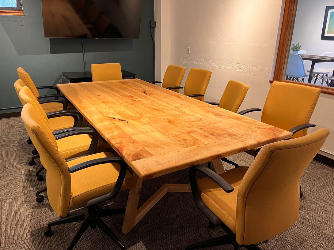 Conference room with a large wooden table and yellow chairs.