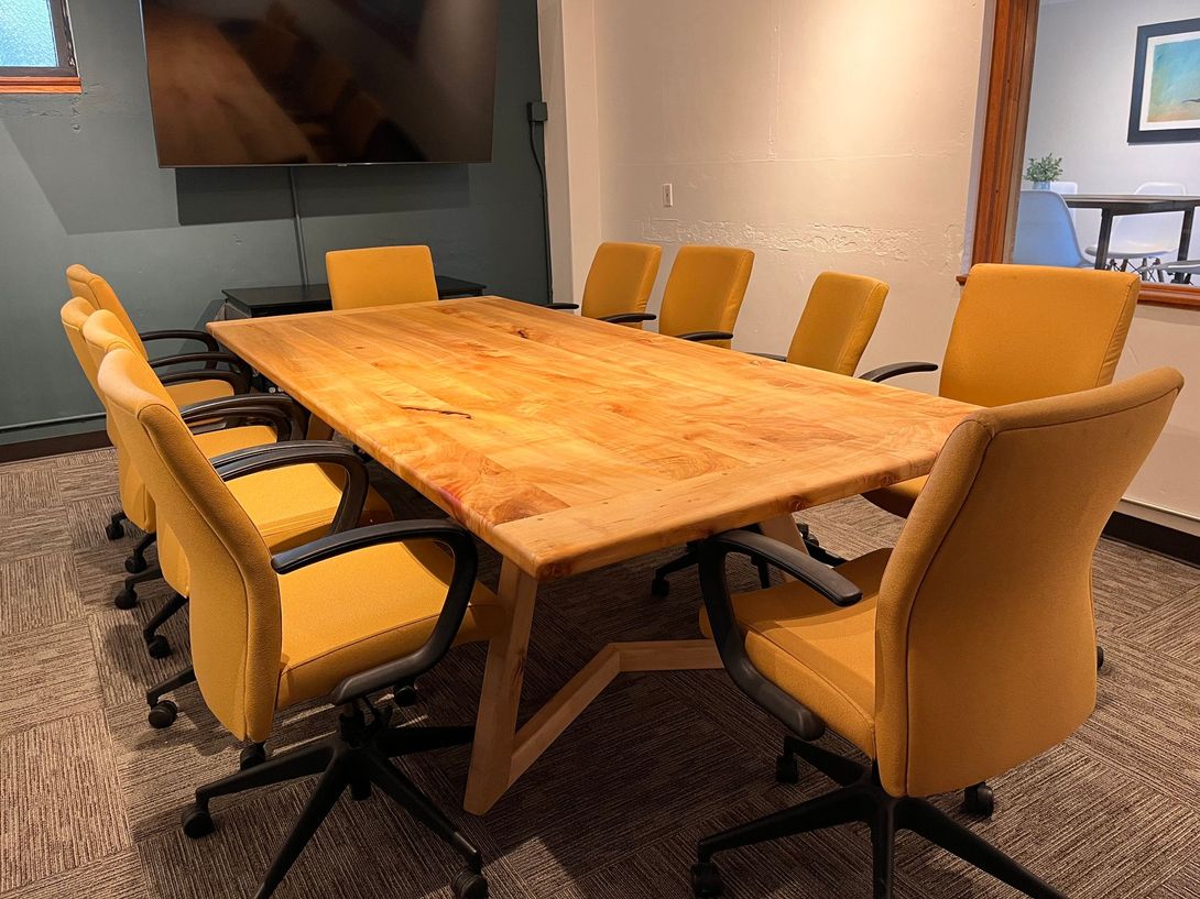 Conference room with a large wooden table and yellow chairs.