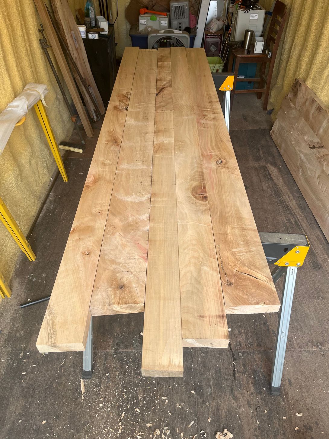Wooden planks arranged on sawhorses, forming a table top in a workshop.