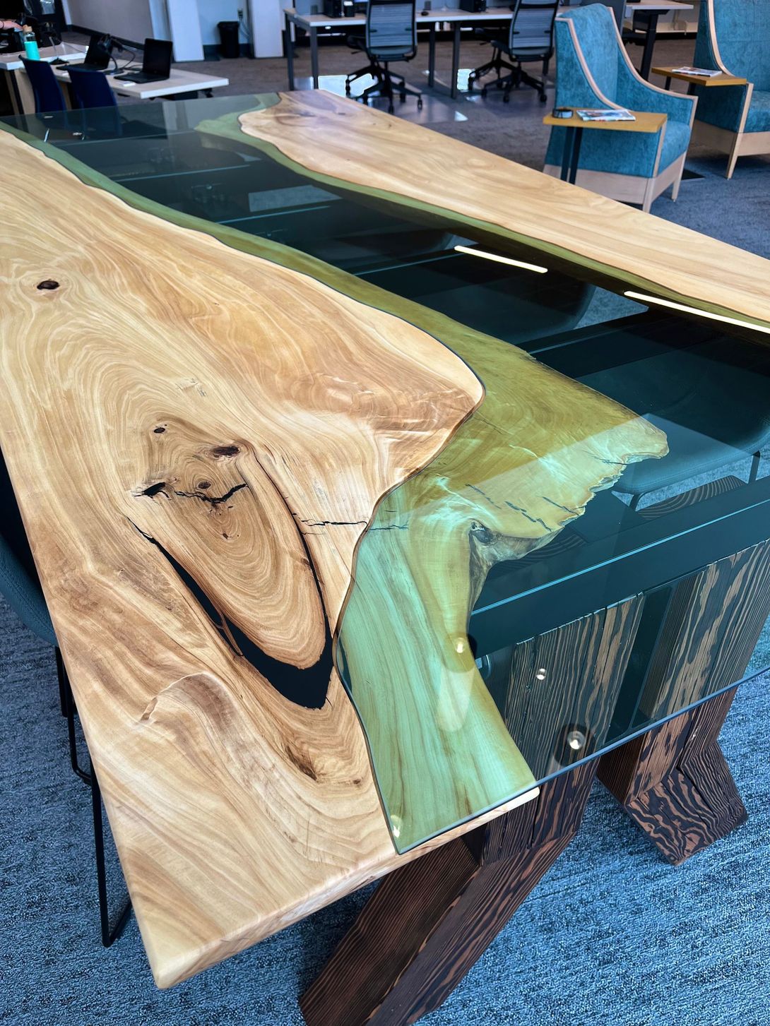 Wooden desk with live edge, filled with green resin, in an office setting.