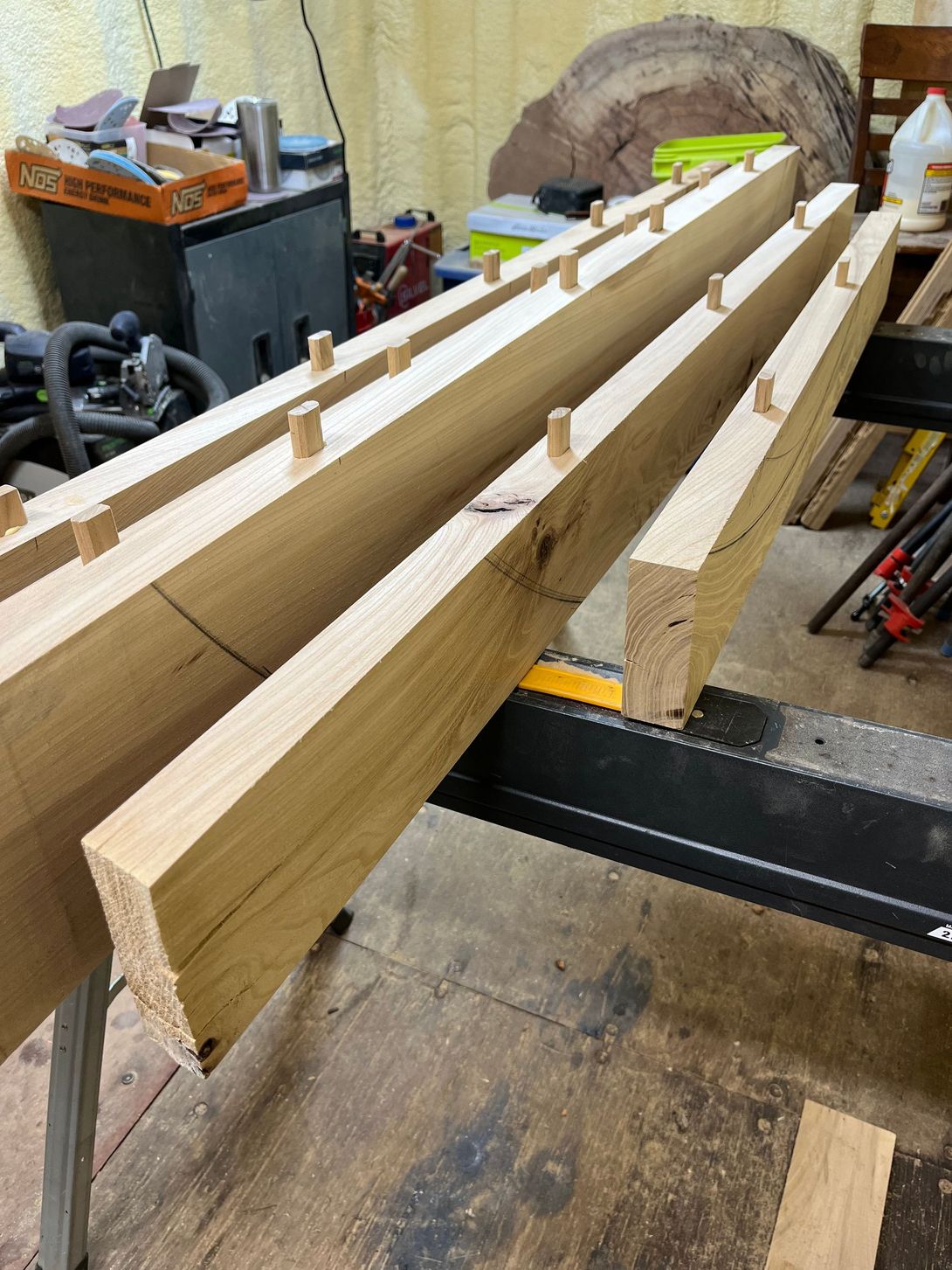 Wooden beams with pegs set in rows, on a workbench in a workshop.