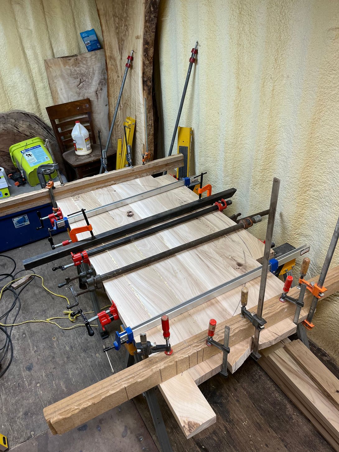 Woodworkers clamping wood planks together in a workshop.